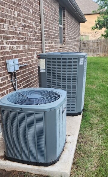 Residential air conditioning condenser units beside an Austin, TX home