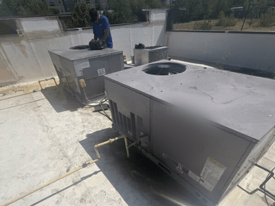 Technician servicing gas-fired commercial rooftop HVAC units before heating season in Austin, TX