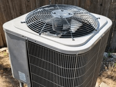 Home heat pump outdoor unit beside a wood fence in Austin, TX, after a compressor replacement