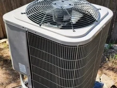 Outdoor heat pump condenser unit beside a wood fence at an Austin, TX home